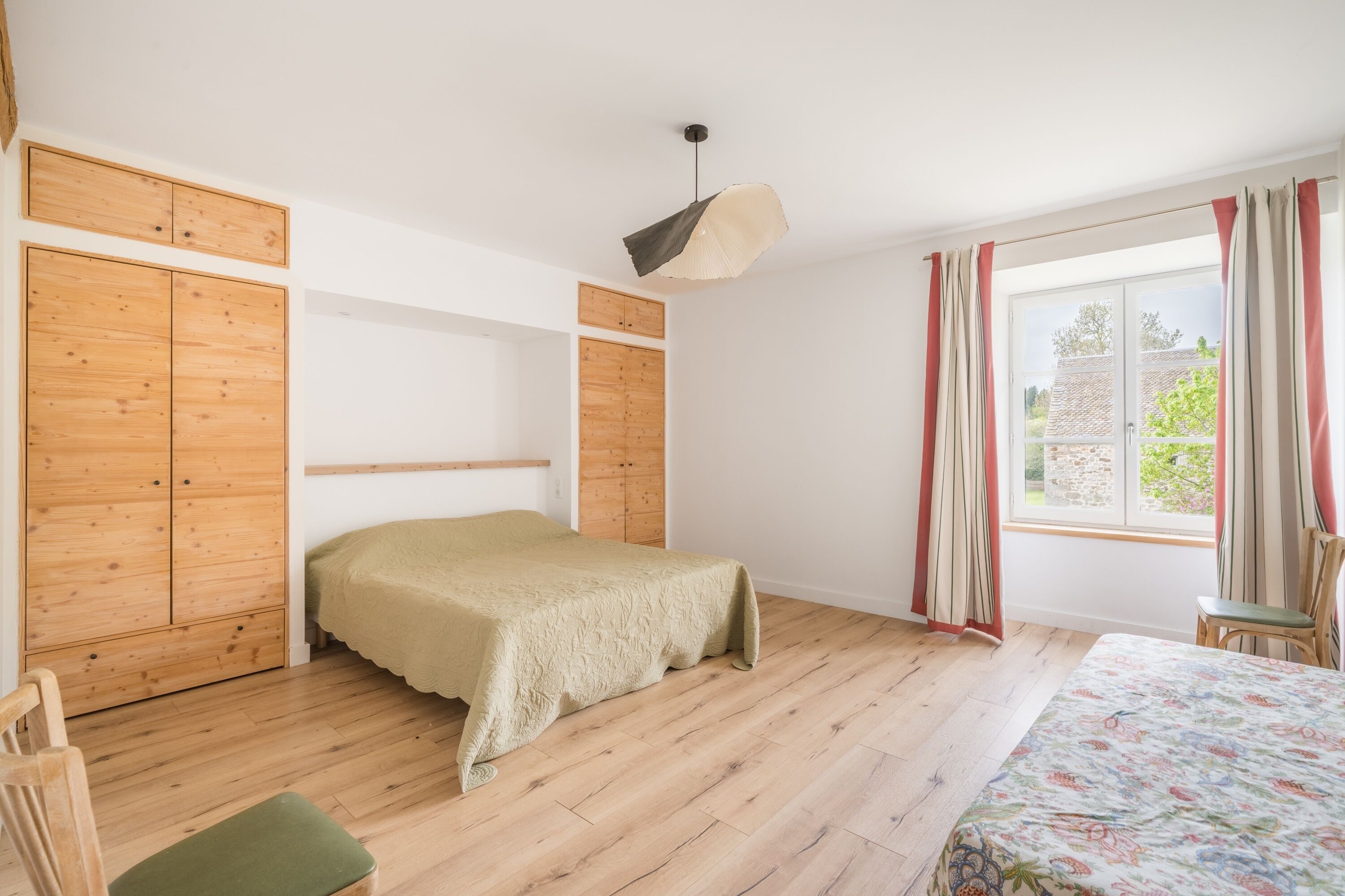 A bedroom with a bed, wooden wardrobe, and a window with curtains.