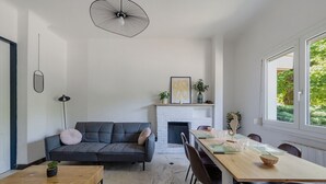 A modern living room with a sofa, coffee table, fireplace, dining table, and chairs. - Le Spatiozo - Appt aux Abatilles, proche plage (Arcachon)