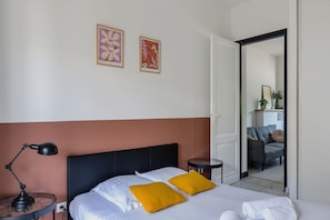 Een hotelkamer met een bed, twee kussens, een nachtkastje, een lamp en een spiegel.