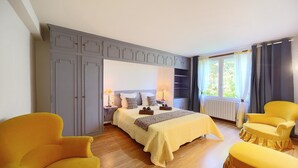 A bedroom with a bed, two yellow armchairs, a grey wardrobe, and a window with curtains. - Le Frêne - Maison familiale au calme pour 10 (Vaour)