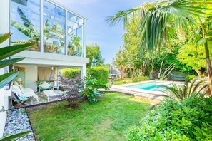Ein modernes Haus mit Glasfassade, Schwimmbad und einem gepflegten Garten.