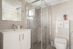 A modern bathroom with a glass shower enclosure, a white sink, and a toilet. - Mati Studio with Mountain View, Wi-Fi and Air Conditioning (Nydri)