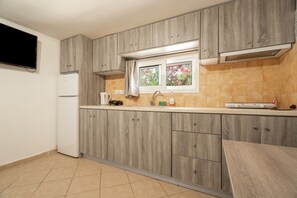 A kitchen with wooden cabinets, a window with a view, a white refrigerator, and a tiled backsplash. - Mati Studio with Mountain View, Wi-Fi and Air Conditioning (Nydri)