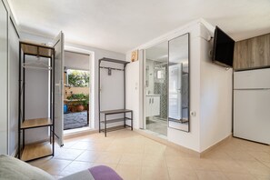 A compact kitchen with a refrigerator, a TV mounted on the wall, and a sliding glass door leading to a patio area. - Mati Studio with Mountain View, Wi-Fi and Air Conditioning (Nydri)