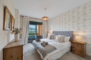 A bedroom with a bed, bedside tables, a window with curtains, and a view of greenery outside. - Stylish Atalaya Apartment with Terrace, Pool and Sea Views (El Paraíso)