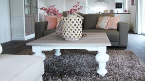 A modern living room with a sofa, a coffee table, and decorative vases. - Holiday Home in Nijkerk With Terrace (Nijkerk)