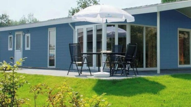 A single-story building with a covered patio area featuring a table and chairs. - Holiday Home in Nijkerk With Terrace (Nijkerk)