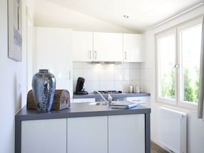 A modern kitchen with white cabinets, a gas stove, a coffee maker, and a large window. - Holiday Home in Nijkerk With Terrace (Nijkerk)