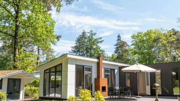 Moderni talo, jossa on patio, savupiippu ja katettu ulkotila oleskelua varten.