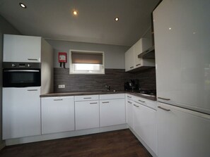 A modern kitchen with white cabinets, a built-in oven, a window above the sink, and a coffee maker. - Holiday Home in Dordrecht With Terrace (Dordrecht)