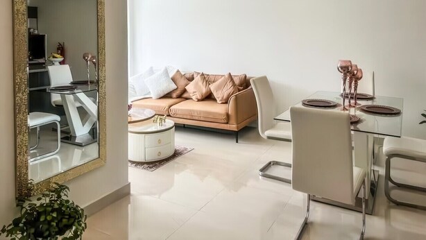 Ein modernes Wohnzimmer mit einem beigen Sofa, einem Glastisch und einem großen Spiegel.
