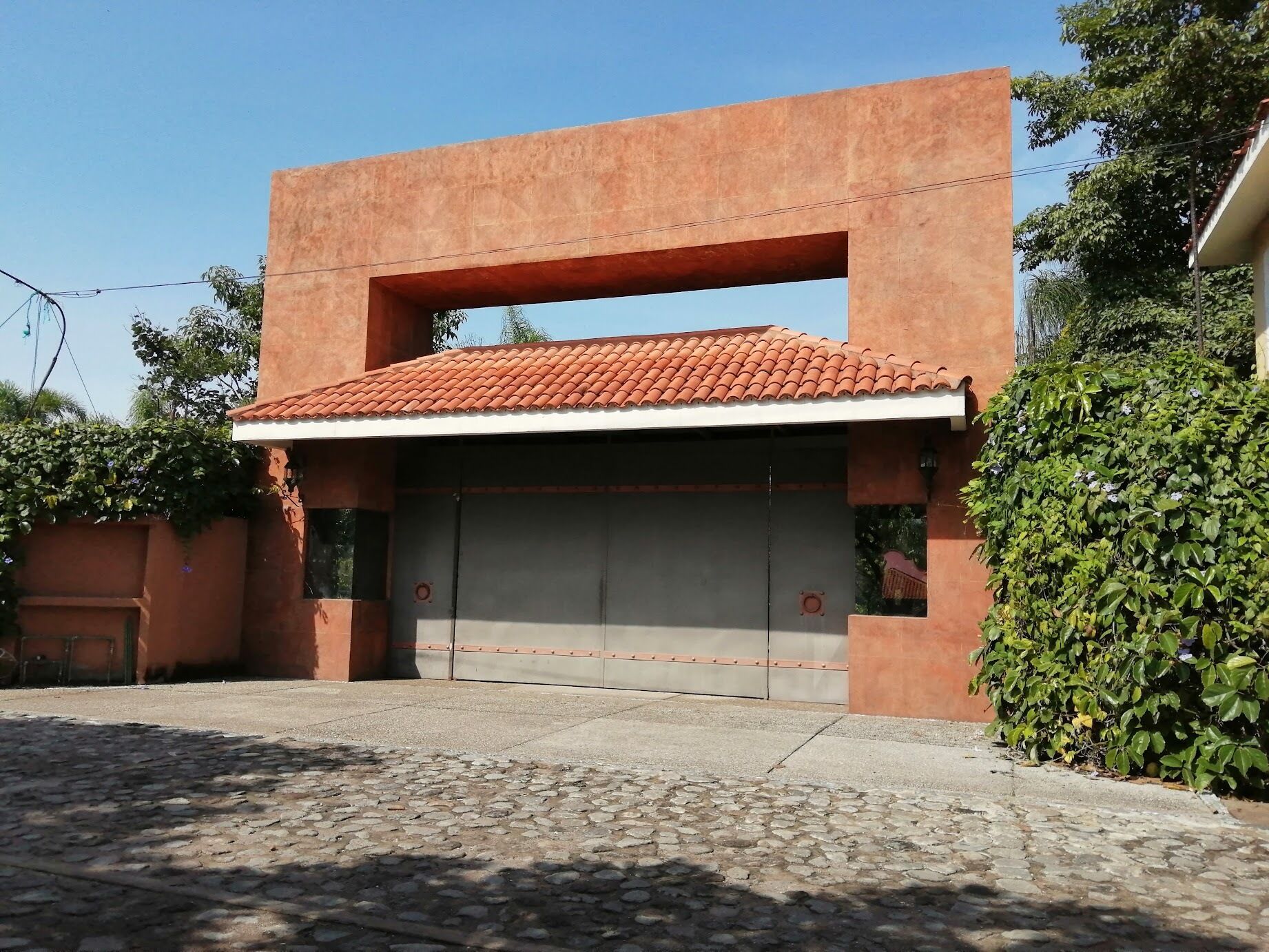 Un edificio con techo plano, puerta de garaje y entrada pavimentada.