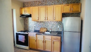 Una cocina con armarios de madera, estufa, fregadero y refrigerador.