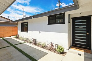 Une maison moderne avec une porte noire, une petite fenêtre et un paillasson.