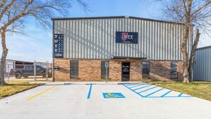 Un bâtiment avec une enseigne indiquant « TUTT TRAINING HOUSE » et une place de stationnement accessible aux personnes en fauteuil roulant.
