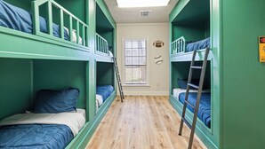 Une chambre avec des lits superposés, une fenêtre avec des stores et une échelle.
