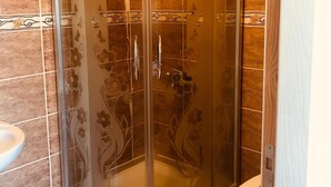 A glass-enclosed shower stall with a curved design, a toilet, and a sink. - Hayal Butik Otel (Adalar)