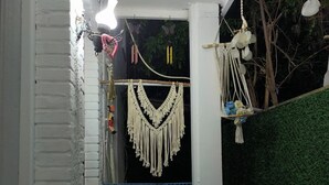 A narrow balcony with macramé wall hangings, a small table, and a chair. - Hayal Butik Otel (Adalar)
