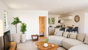 Uma sala de estar moderna com um sofá seccional, uma mesa de centro de madeira e duas plantas em vasos.