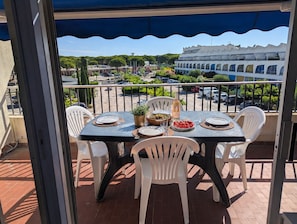 Ein Balkon mit Tisch für zwei Personen, Stühlen, einer Weinflasche und einer Obstschale.