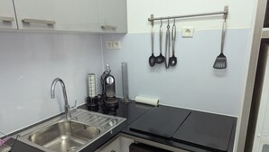 A modern kitchen with a stainless steel sink, a coffee machine, and a black stove. - Sol-y-Days Jardins du port large terrace and swimming pool (Le Grau-du-Roi)