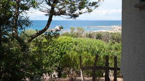 A stone pathway leading to a view of the sea, surrounded by greenery and a wooden fence. - Domus Gallesi by Wonderful Italy (Aglientu)