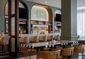 A bar area with a checkered table, bar stools, and shelves of bottles.
