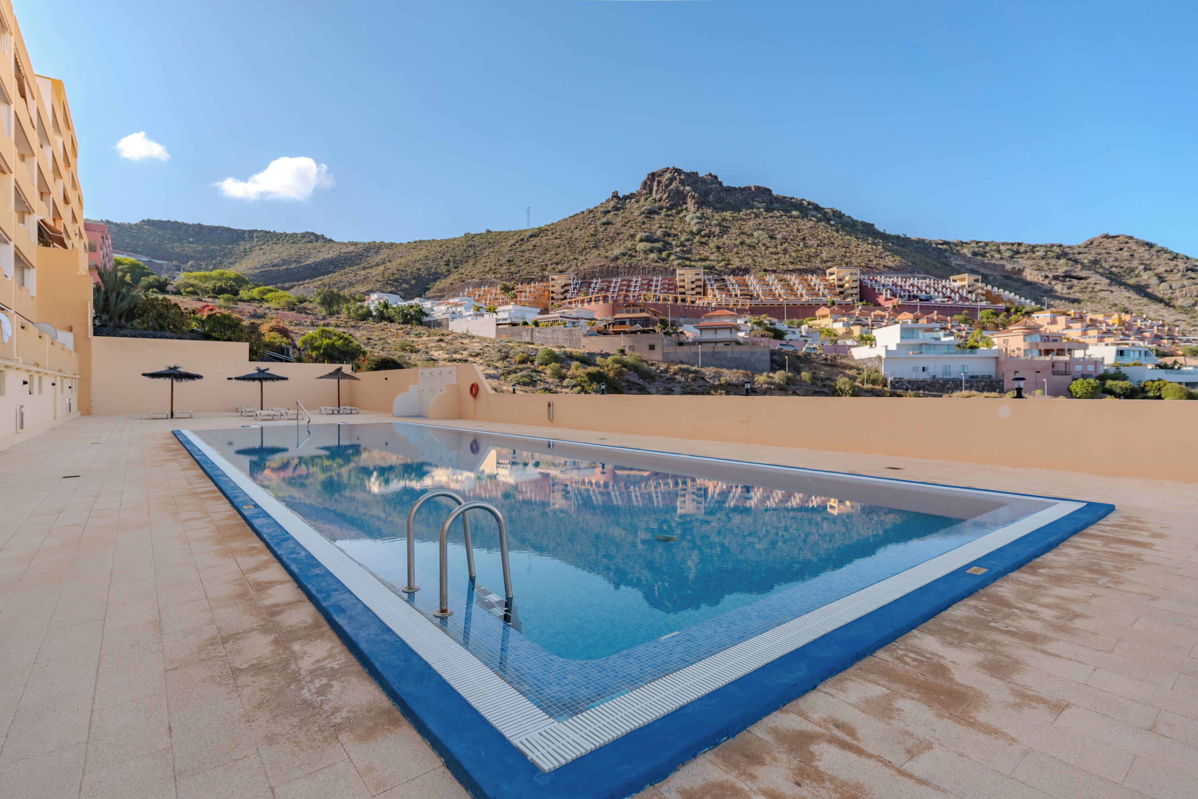 A swimming pool with a view of a town and mountains in the background.