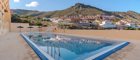 A swimming pool with a view of a town and mountains in the background.