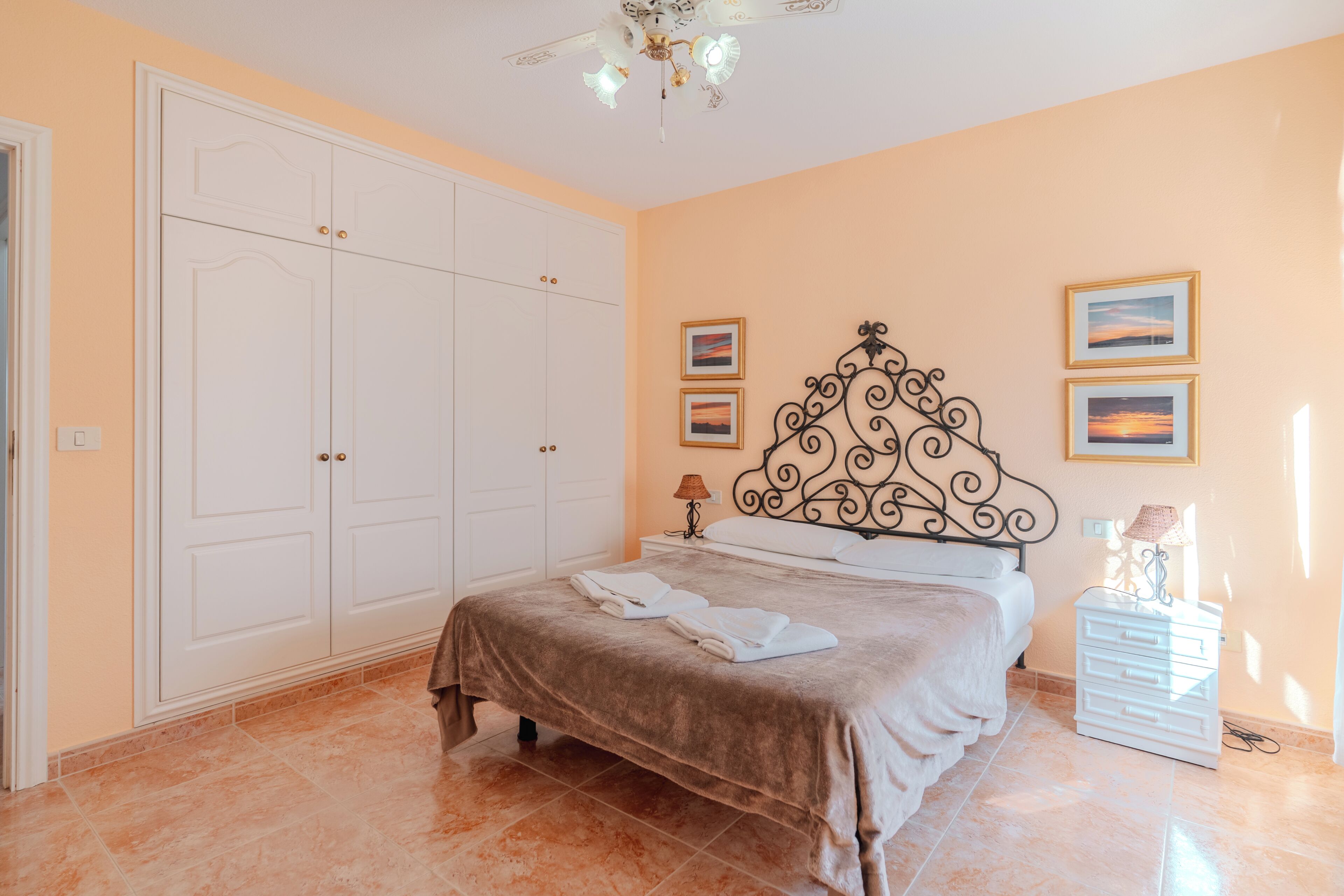 Une chambre à coucher comprenant un lit, une armoire, une table de chevet et des œuvres d’art mural.