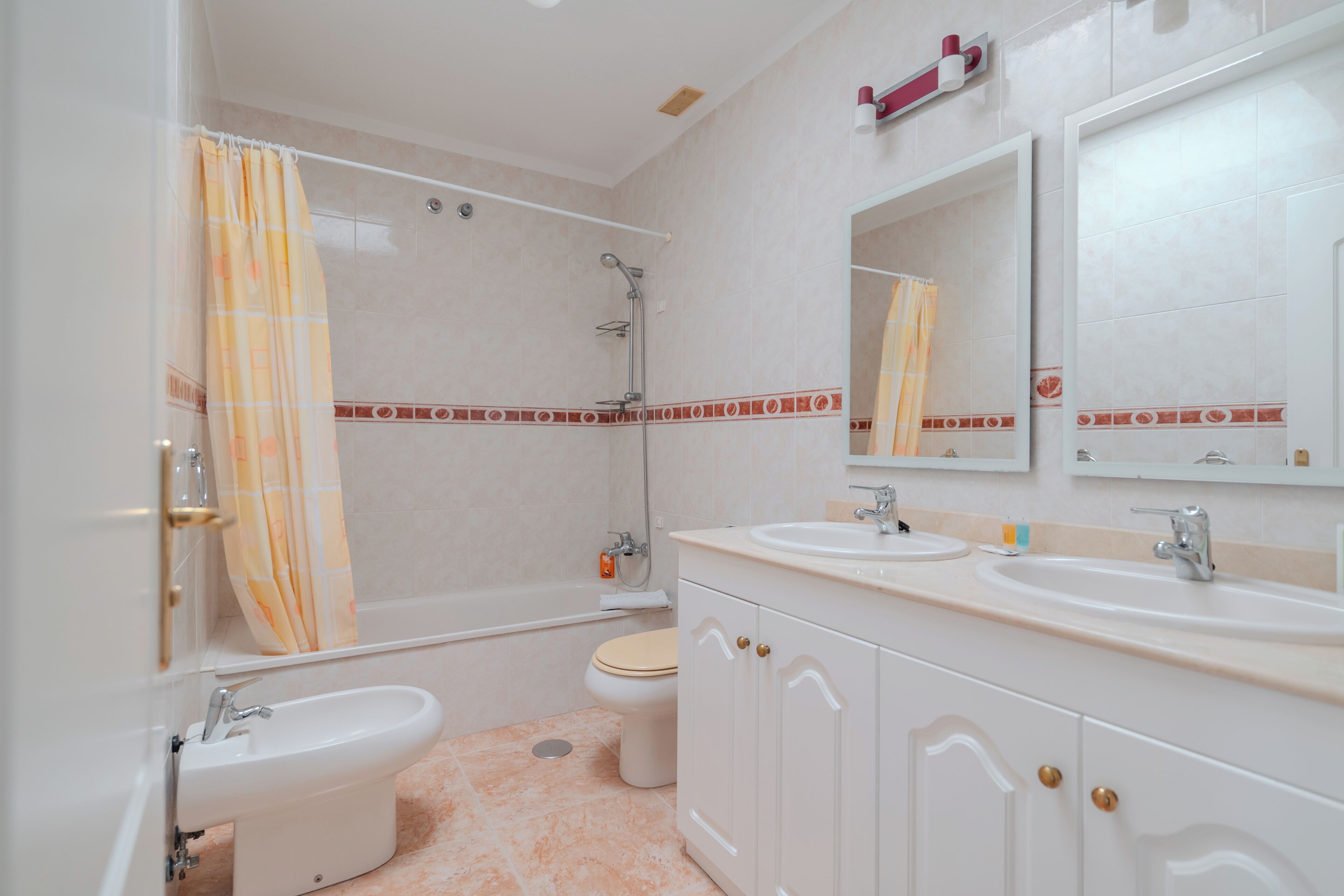 A bathroom with a bathtub, toilet, bidet, and two sinks.