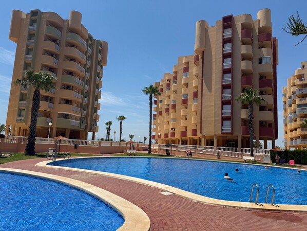 A swimming pool with a curved edge, surrounded by a brick walkway.