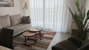 En stue med en sofa, to runde borde, et sofabord, en lampe og en stor plante.