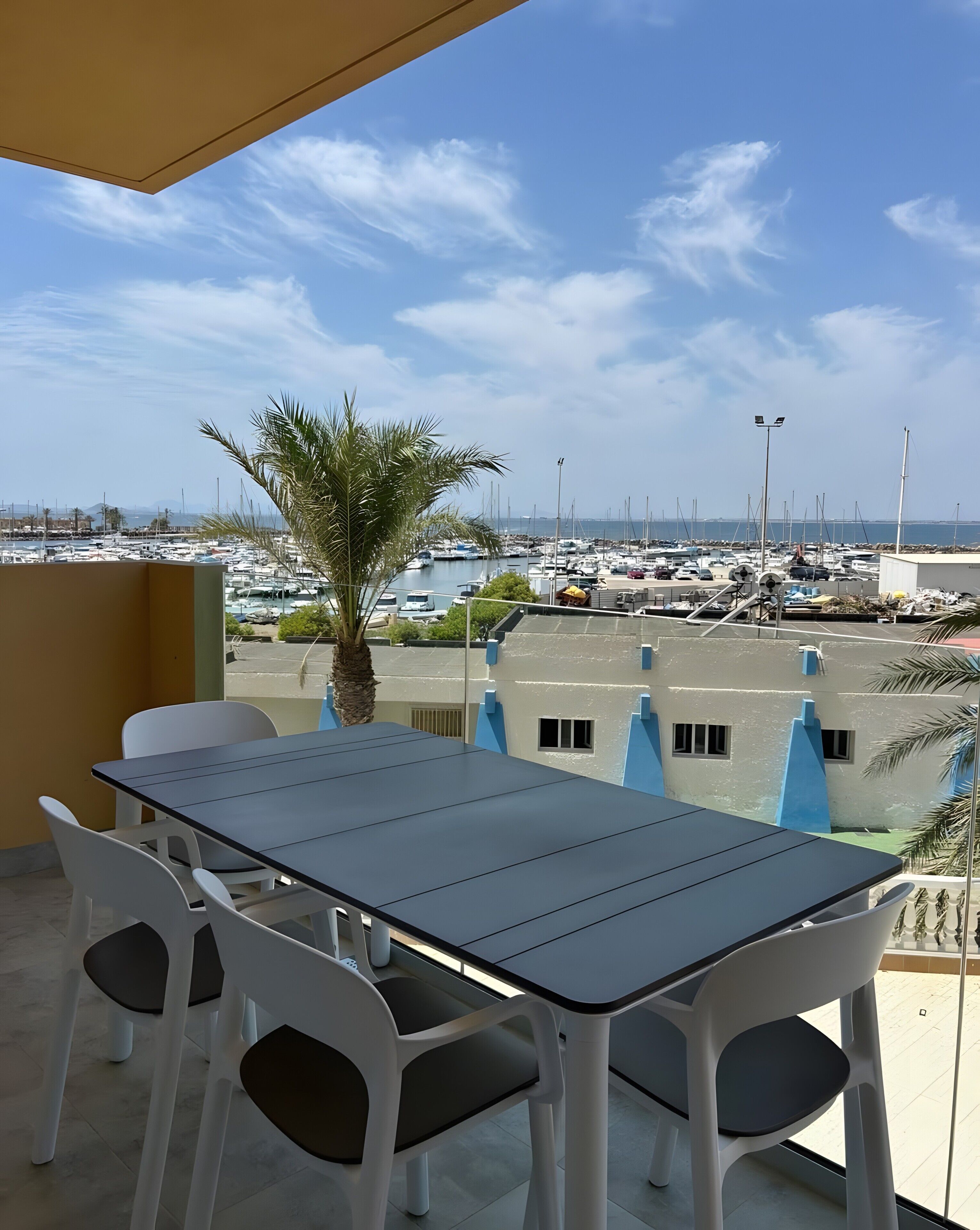 A balcony with a table and chairs, overlooking a marina with boats.