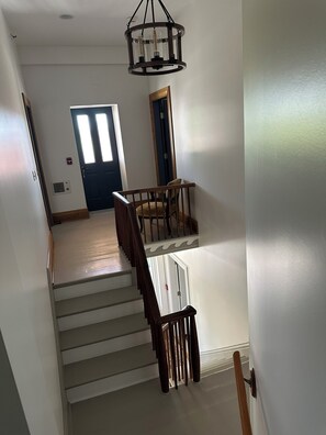 A staircase with wooden railings, a dining area with a table and chairs, and a door with a window.