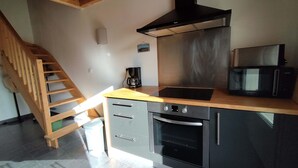 Una cocina con una escalera de madera, una cafetera, un microondas y un horno.