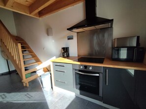 Eine Küche mit Holzboden, einer Kaffeemaschine, einer Mikrowelle und einem Backofen.