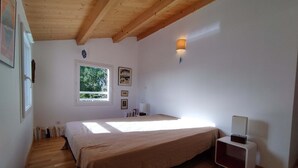 Un dormitorio con cama, ventana, luz empotrada y mesita de noche.