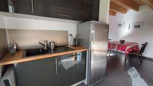Una cocina moderna con armarios oscuros, un refrigerador de acero inoxidable y una encimera de madera.