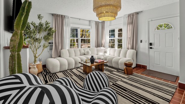 Ein Wohnzimmer mit einem Ecksofa, einem Couchtisch, einer großen Sukkulante und einem Fernseher.