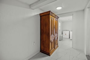 Ein Flur mit einem Holzschrank, einer Waschmaschine und einem Trockner im Hintergrund.