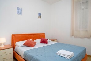 Une chambre avec un lit simple, une table de chevet, une commode et deux petits tableaux décoratifs.