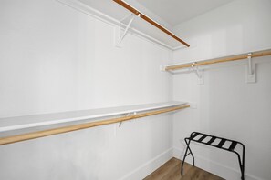 Een kamer met witte muren, houten balken en een zwarte metalen bank.