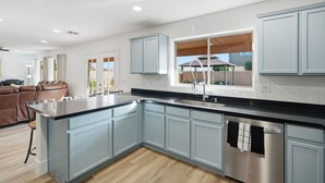 A modern kitchen with light blue cabinets, a stainless steel dishwasher, and a large island. - Marvelous 4-bedroom cottage with billiard room in Casa Grande (Casa Grande)