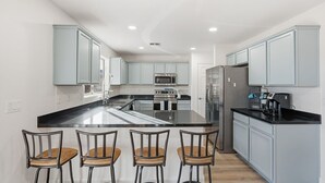 A modern kitchen with a central island, bar stools, stainless steel appliances, and light blue cabinetry. - Marvelous 4-bedroom cottage with billiard room in Casa Grande (Casa Grande)