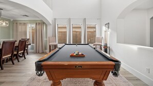 A pool table in a spacious room with a dining area and a staircase. - Marvelous 4-bedroom cottage with billiard room in Casa Grande (Casa Grande)
