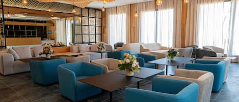A spacious lobby with modern seating, a wooden ceiling, and large windows.