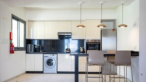 Una cocina moderna con lavadora, hervidor y comedor con sillas.