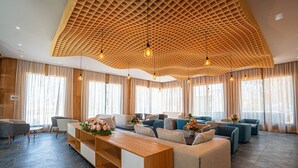 Un interior moderno con techo de madera, varias zonas de estar y amplios ventanales.