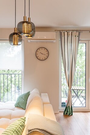 Ein modernes Wohnzimmer mit einer Couch, einer Wanduhr und einem Balkon mit Blick.